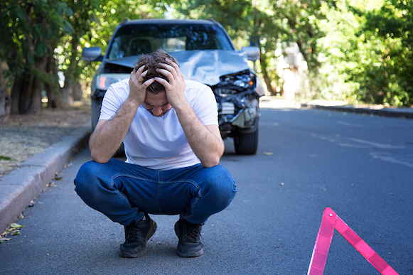 Man crouching in front of car accident